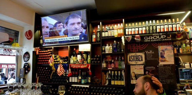 A man sits in a bar while the television displays images of ETA leader Jose Antonio Urrutikoetxea, alias Josu Ternera, during the announcement of the dissolution of armed Basque separatists ETA, in Bilbao