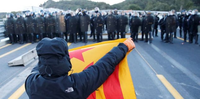 A man holds an Estelada (Catalan separatist flag) in front of French police officers at the AP-7 highway
