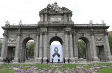 Poster cu o panglică neagră, plasat pe faţada unui celebru monument din Madrid, Puerta de Alcalá